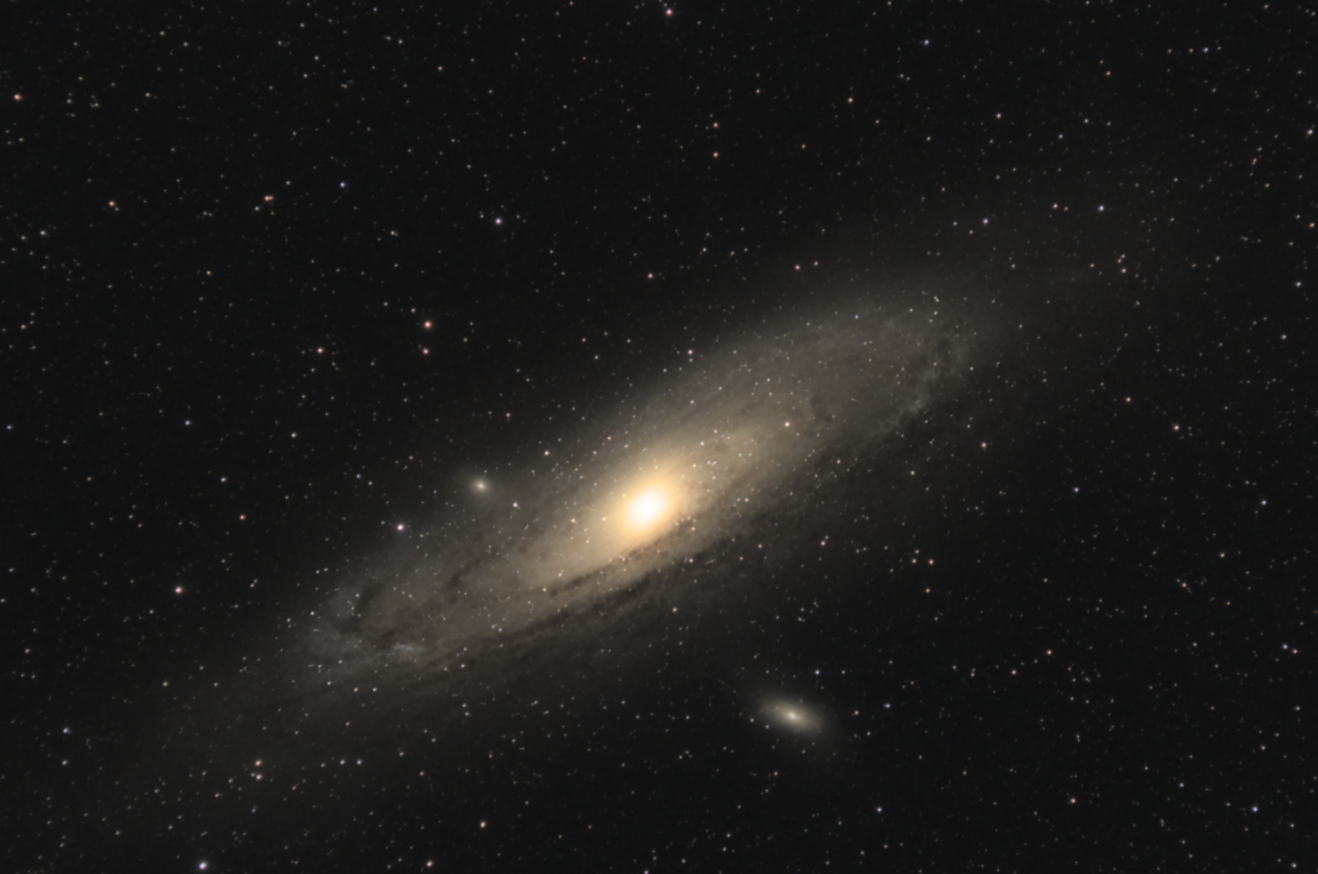 A huge spiral galaxy seen obliquely, covering most of the frame of the picture. The galaxy features several dark dust lanes and a brilliant yellowish core.